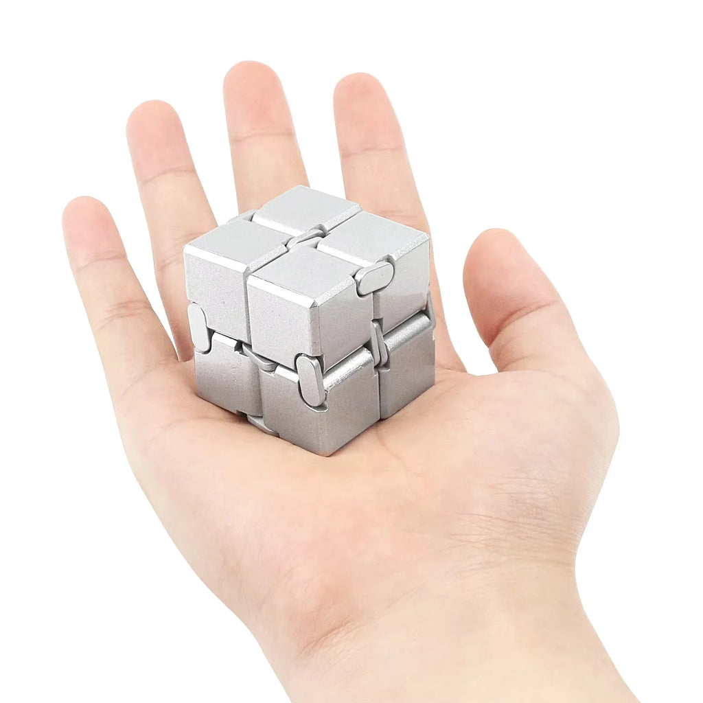A hand holding a silver alloy infinity cube, showing how it sits in the palm.