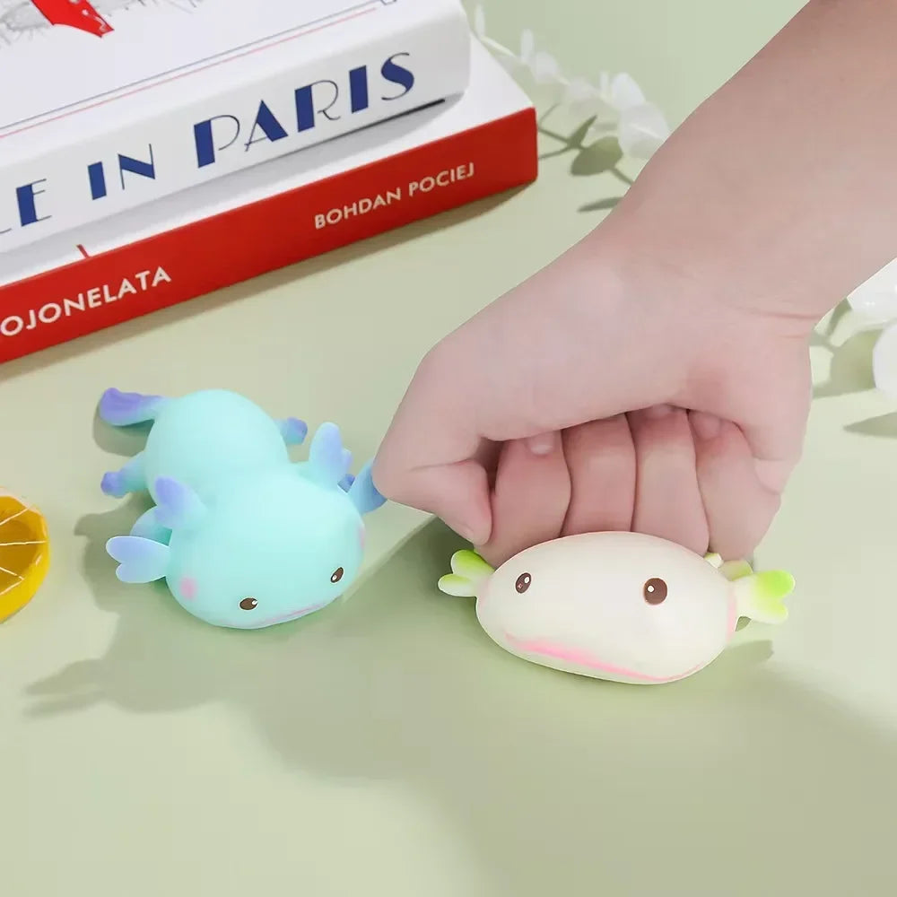 A hand pinching a white axolotl squishy to show the slow-rebound squeeze.