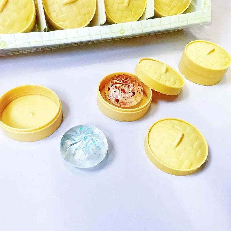 Mini soup dumpling squishies with one steamer case open, showing the glittery jelly bun inside.