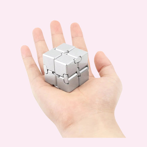 Silver alloy infinity cube fidget toy held in a hand on a pink background - Trendy Toyz AU