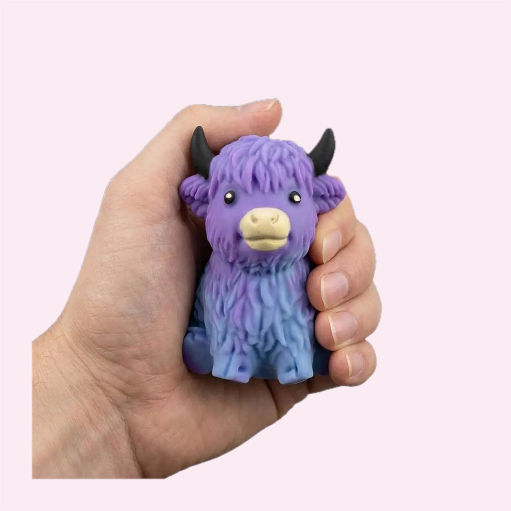 Purple Highland Cow Squishy being squeezed in a hand on a pink background - Trendy Toyz AU