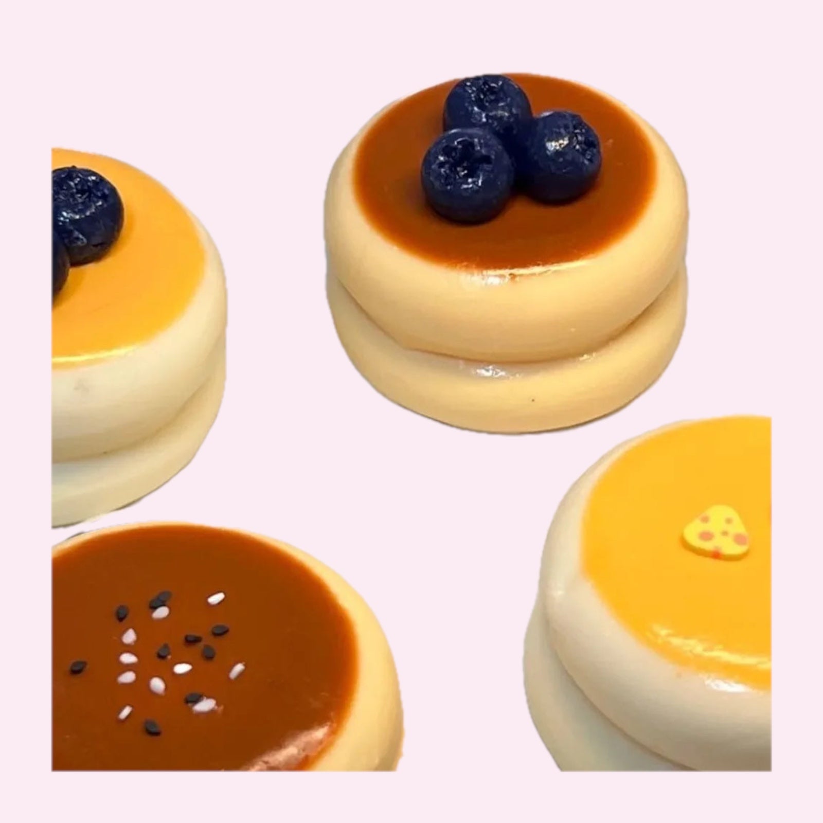 Four souffle pancake squishies in blueberry, strawberry, yellow and pink toppings on a pink background - Trendy Toyz AU