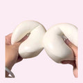 Giant yoghurt bun squishy being squashed with two hands on a pink background - Trendy Toyz AU